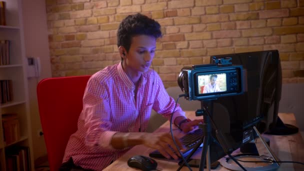 Closeup shoot of young indian attractive male blogger in vibes playing video games on the computer streaming live talking on camera indoors in the cozy apartment — Stock Video