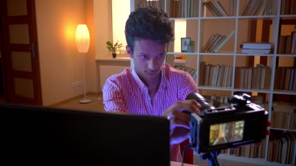 Съемки крупным планом молодого индийского привлекательного мужчины-видеоблоггера в флюидах, играющего в видеоигры на компьютере, транслирующиеся в прямом эфире на камеру в уютной квартире — стоковое видео