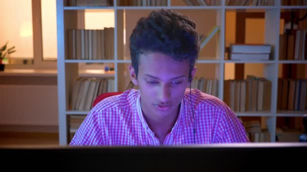 Closeup shoot af ung indisk attraktiv mandlig gamer i vibes, der spiller på computerens streaming og taler på kamera indendørs i den hyggelige lejlighed – Stock-video