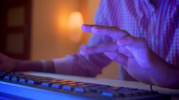 Κοντινά πλάνα του Ινδικού αρσενικό blogger χέρια δακτυλογραφούν στον υπολογιστή σε εσωτερικούς χώρους σε ένα άνετο διαμέρισμα με νέον φως — Αρχείο Βίντεο