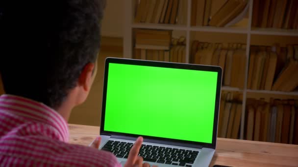 실내 사무실에서 녹색 화면이있는 노트북을 사용하여 아라비아 젊은 사업가의 클로즈업 백뷰 촬영 — 비디오