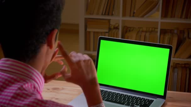 실내 작업장에서 녹색 크로마 스크린이있는 노트북에서 화상 통화를하는 인도 의 젊은 사업가의 클로즈업 백뷰 촬영 — 비디오