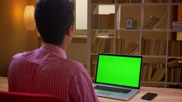 Primo piano vista posteriore ripresa di indiano giovane uomo d'affari avendo una videochiamata sul computer portatile con schermo chiave cromatica verde in ufficio al chiuso — Video Stock