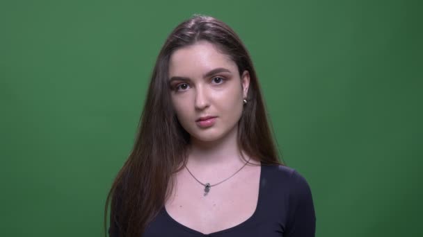 Nahaufnahme Porträt der jungen hübschen brünetten Frau Blick auf Kamera mit Hintergrund isoliert auf grün — Stockvideo