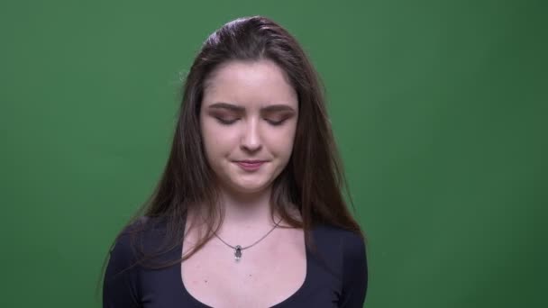 Genç güzel esmer kadın yakın çekim portre saçlarını atarak ve yeşil izole arka plan ile karışıklık ile kamera bakıyor — Stok video