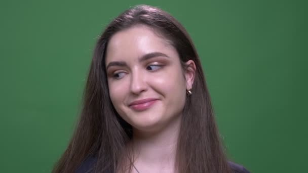 Κοντινό πλάνο του νεαρού όμορφη μελαχρινή γυναίκα που δείχνει τη γλώσσα και κάνοντας αστείες εκφράσεις του προσώπου κοιτάζοντας την κάμερα με φόντο απομονωμένη στο πράσινο — Αρχείο Βίντεο