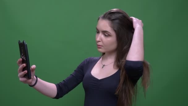 Gros plan portrait de jeune jolie brune femelle prenant selfies mignons sur le téléphone avec fond isolé sur vert — Video