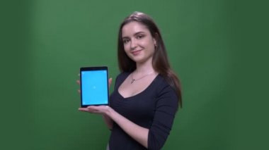 Tablet kullanarak genç güzel esmer kadın Closeup portre ve yeşil izole arka plan ile kameraya mavi ekran gösteren