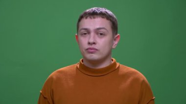 Genç çekici beyaz erkek yakın çekim sıkılmış ve yeşil izole arka plan ile kamera bakarak rahatsız