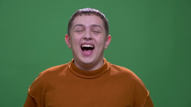 Closeup shoot of young attractive caucasian male smiling and laughing happily looking at camera with background isolated on green — Stock Video