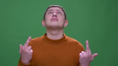 Parmaklarını çapraz olan genç çekici beyaz erkek closeup çekim yeşil izole arka plan ile umutlu olmak