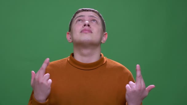 Съемки крупным планом молодого привлекательного кавказского мужчины со скрещенными пальцами на фоне изолированного на зеленом фоне — стоковое видео