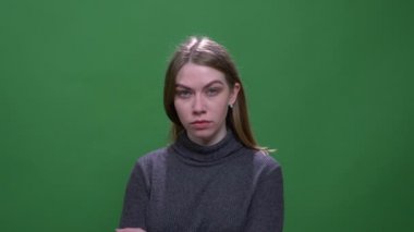 Ciddi sarışın model yeşil renk arka plan izole hor ile kameraya izlerken.