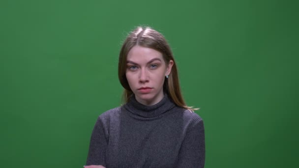 Σοβαρή ξανθιά μοντέλο βλέποντας στην κάμερα με περιφρόνηση απομονώνονται σε πράσινο χρωματικό φόντο. — Αρχείο Βίντεο