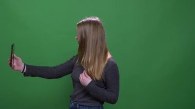 Yeşil renk arka planda izole akıllı telefon kullanarak selfie yapma Pretty sarışın iş kadını.