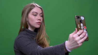 Güzel sarışın iş kadını yeşil renk arka plan izole akıllı telefon kullanarak selfie yapma.