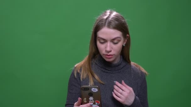 Bonita mulher de negócios loira corrige cabelo assistindo em câmera frontal no telefone isolado no fundo do cromo verde . — Vídeo de Stock