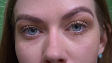 Sarışın modelin yakın çekim göz portresi kameraya sakin ve dikkatle saatler.