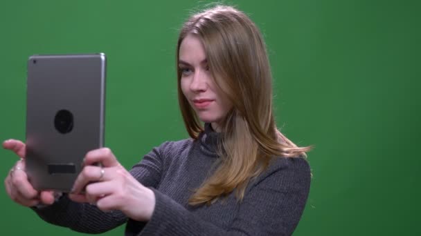 Gyönyörű szőke üzletasszony hogy selfies segítségével tabletta izolált zöld chroma háttér. — Stock videók