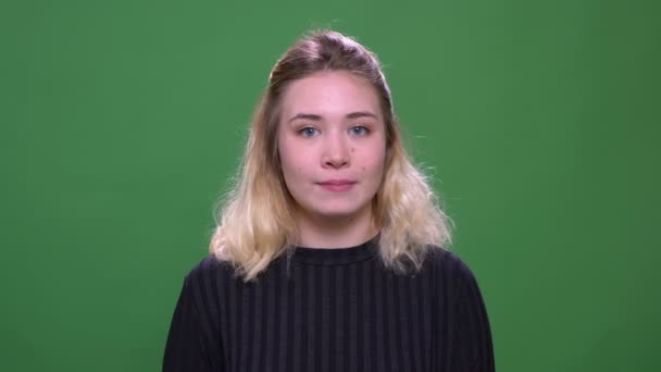 Close-up retrato de jovem bonita loira caucasiano feminino acenando oi sorrindo olhando para a câmera com fundo isolado no verde — Vídeo de Stock