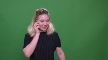 Yeşil izole arka plan ile bir telefon görüşmesi olan genç güzel sarışın beyaz beyaz kadın Closeup portre