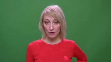 Orta yaşlı sarışın kısa saçlı kadın yeşil renk arka plan üzerinde izole dudaklarını gösteren kamera ile flört.