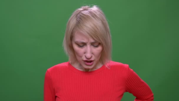 Middle-aged blonde short-haired model turns head negatively to refuse isolated on green background. — Stock Video