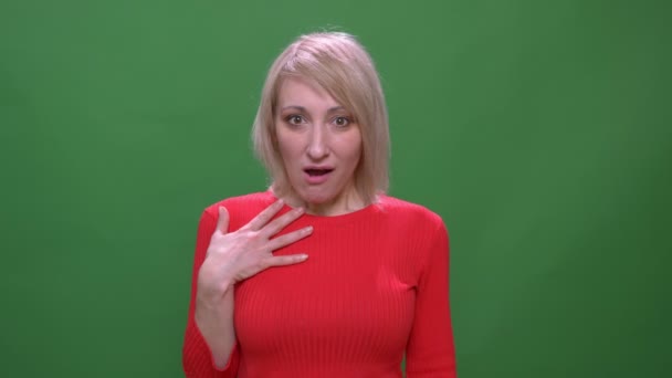 Middelbare leeftijd blonde kortharige model toont positieve verrassing in camera geïsoleerd op groene achtergrond. — Stockvideo