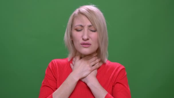 Middle-aged blonde short-haired model suffers from flu and sore throat isolated on green background. — Stock Video