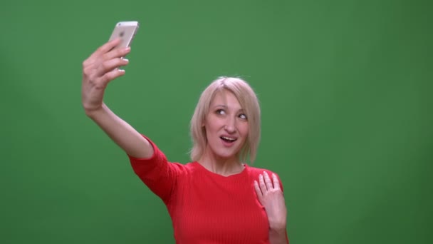 Middelbare leeftijd kortharige zakenvrouw maakt selfies op smartphone geïsoleerd op groene Chromakey achtergrond. — Stockvideo