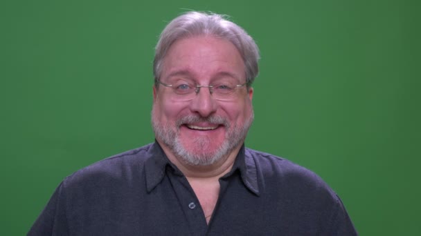 Senior grauhaarige Geschäftsmann mit Brille lächelt in die Kamera isoliert auf grünem Chromakey-Hintergrund. — Stockvideo