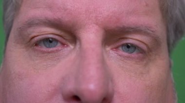 Üst düzey gri saçlı adamın yakın çekim göz portresi yeşil renk arka planda izole kamera içine ne yazık ki saatler.