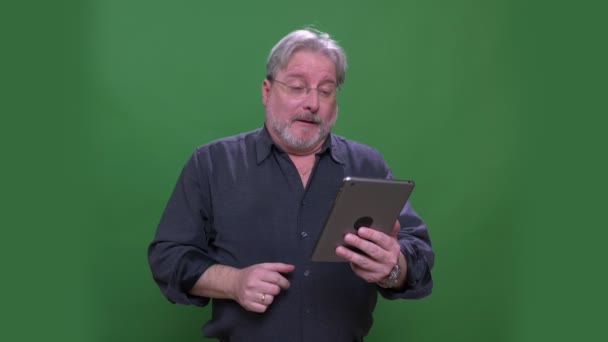 Homem americano de cabelos grisalhos sênior em óculos conversando em videochat na guia isolado em fundo cromado verde . — Vídeo de Stock