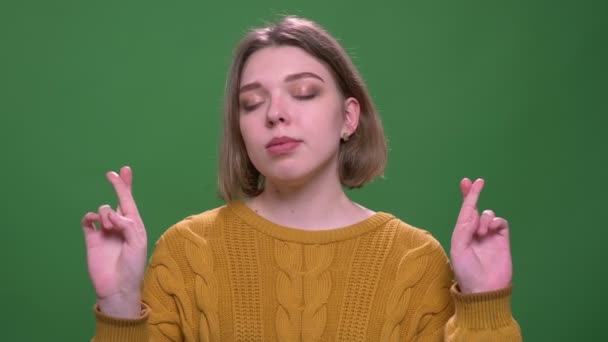 緑の上に隔離された背景を持つカメラを見て彼女の指を交差させた若い魅力的な短い髪の女性のクローズアップ撮影 — ストック動画