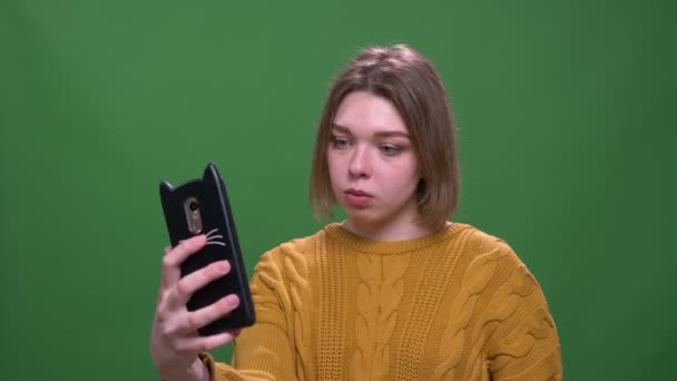 Närbild shoot av unga attraktiva korthårig kvinna tar selfies på telefonen med bakgrund isolerad på grön — Stockvideo