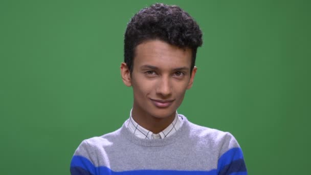 Съемки крупным планом молодого привлекательного индийского мужчины, счастливо улыбающегося, глядя в камеру на фоне, изолированном на зеленом — стоковое видео