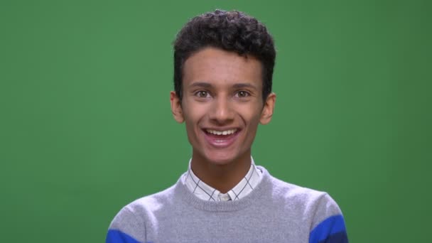 Syuting jarak dekat laki-laki muda yang menarik menarik India tersenyum riang melihat kamera dengan latar belakang terisolasi di hijau — Stok Video