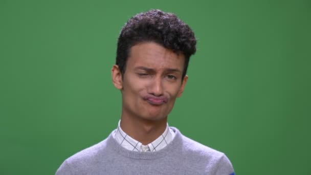 Komik yüz ifadeleri yapma ve yeşil izole arka plan ile kameraya bakarak dil gösteren genç çekici Hintli erkek Closeup ateş — Stok video
