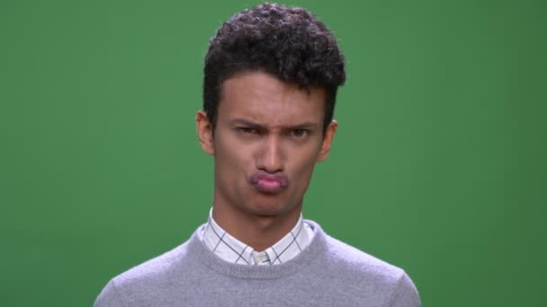 Primer plano de brote de joven atractivo indio masculino haciendo expresiones faciales divertidas mirando a la cámara con el fondo aislado en verde — Vídeo de stock