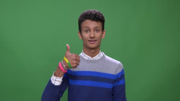 Närbild shoot av unga attraktiva indiska manliga visar tummen upp titta på kamera med bakgrund isolerade på grön — Stockvideo