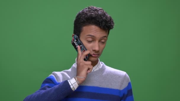 緑の上に隔離された背景を持つ電話を持つ若い魅力的なインドの男性のクローズアップ撮影 — ストック動画