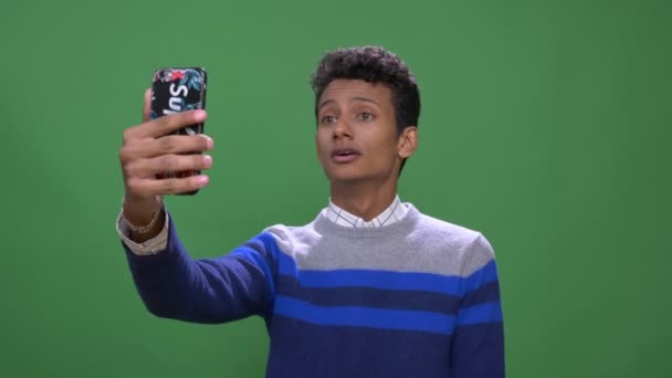 Close-up shoot van jonge aantrekkelijke Indiase man met een videogesprek op de telefoon met achtergrond geïsoleerd op groen — Stockvideo