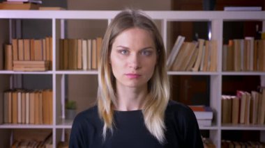 Üniversite kütüphanesinde kapalı kamera bakarak genç çekici kız öğrencinin closeup çekim