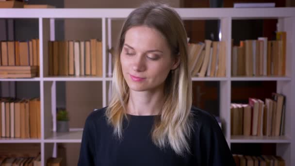 Nahaufnahme einer jungen attraktiven Studentin, die glücklich in die Kamera in der Universitätsbibliothek tanzt — Stockvideo