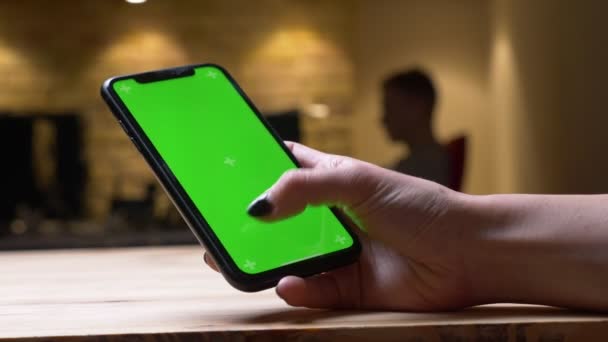 Primer plano de la vista trasera de la sesión de mensajes de texto de la mano femenina en el teléfono con pantalla de croma verde en la oficina en el interior — Vídeos de Stock