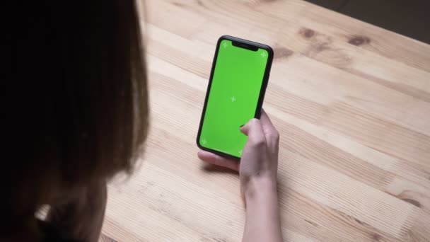 Closeup vissza lőni a női kezében egy telefon, zöld chroma képernyőn az asztalon az irodában beltéri — Stock videók