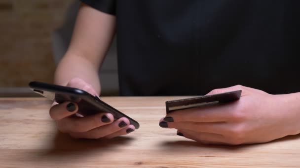 Gros plan de femmes achats à la main en ligne sur le téléphone tenant la carte de crédit dans le bureau à l'intérieur — Video