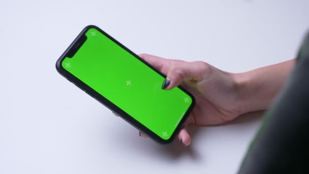 Close-up terug Bekijk shoot of Female hand messaging op de telefoon met groen Chroma scherm op kantoor binnenshuis op het witte Bureau — Stockvideo