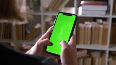 Kapalı kütüphanede yeşil renk ekran ile telefonda mesajlaşma kız öğrencilerin Closeup geri görünümü ateş