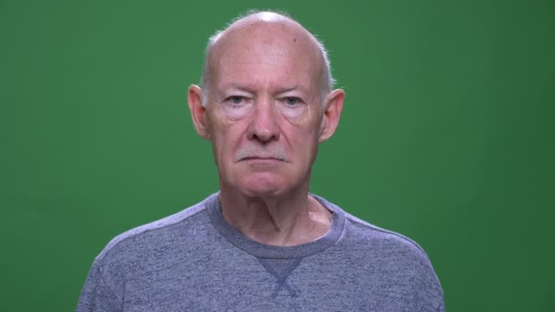 Close-up tiro de idade homem caucasiano sênior olhando para a câmera com fundo isolado no verde — Vídeo de Stock
